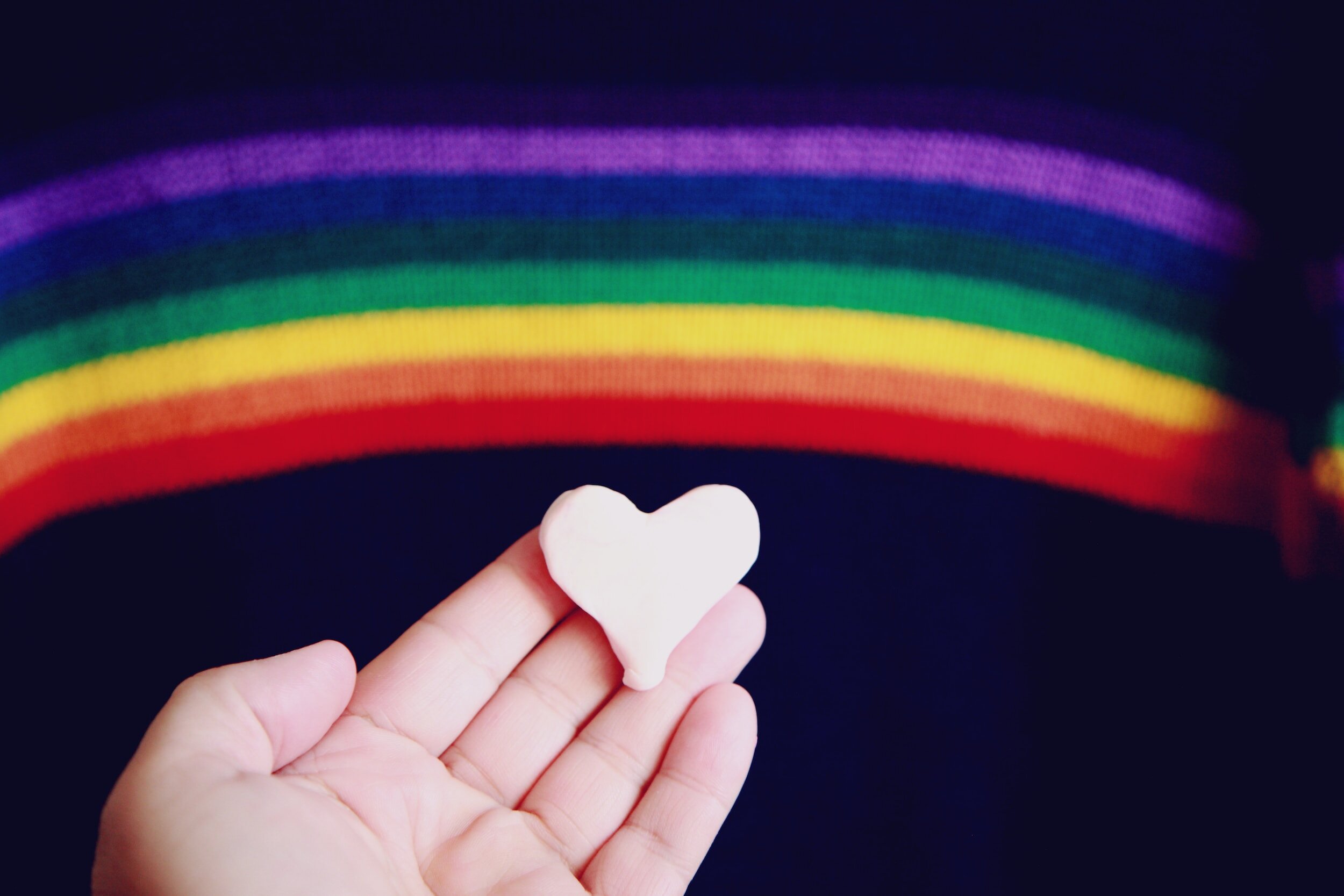hand holding heart with rainbow